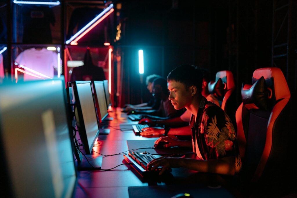 A group of focused gamers playing in a neon-lit gaming room, showcasing intense concentration and modern technology.